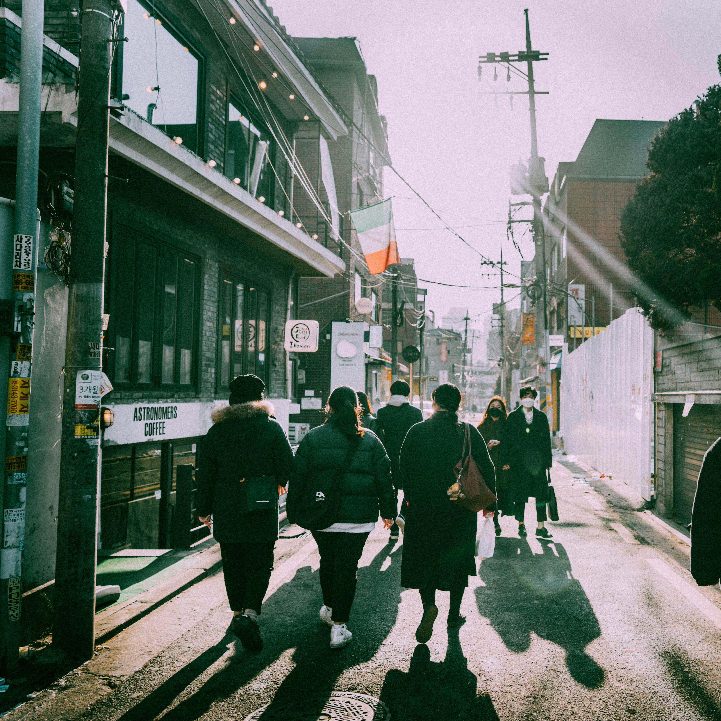People walking along a sunlit neighborhood street